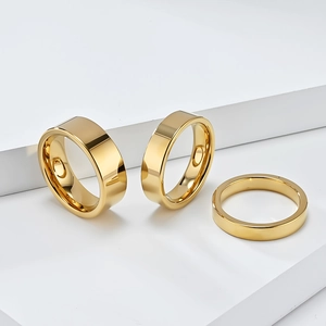 Bagues en acier tungstène doré poli en trois largeurs sur fond blanc minimaliste