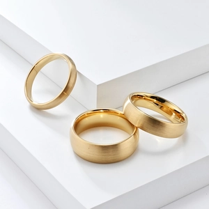 Three gold tungsten rings in 2mm 4mm 6mm widths with brushed matte finish on pedestals