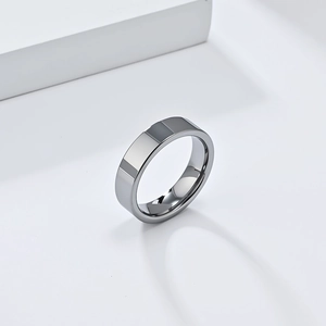 Détail macro d'une bague en acier tungstène poli sur un support géométrique blanc