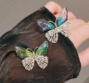 Detail der eleganten Schmetterlingsbrosche mit lila-grünen Flügeln und weißen Zirkonia