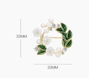 Detail of gardenia wreath brooch with white flowers, pearls, and green enamel leaves
