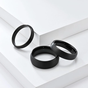 Matte black tungsten steel rings in three widths on white geometric steps display