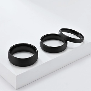 Detailed view of three black tungsten rings with fine brushed finish on geometric display