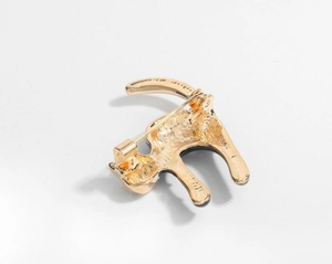 Detail view of the golden metal back and safety pin clasp of the cat brooch