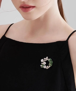 Close-up of gardenia flower brooch with white petals and pearls on a black dress