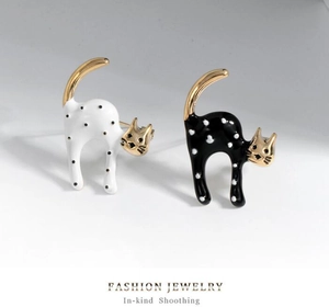 Detailed macro view of cute gold-plated cat earrings with polka dot enamel finish