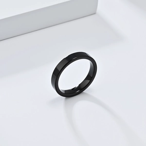 Vue détaillée d'une bague en tungstène noir poli sur un support géométrique blanc épuré