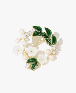 Close-up of golden wreath brooch with white flowers, green enamel leaves, and pearls