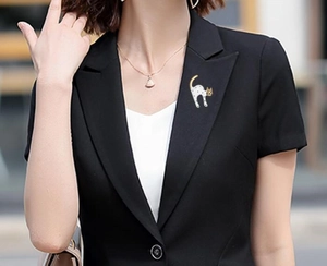 Polka dot cat brooch with gold tail pinned on a black blazer lapel for a stylish look