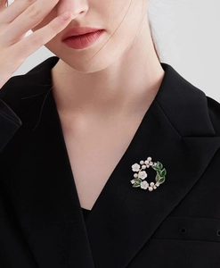 Detailed view of gardenia brooch with white flowers and green leaves on black suit lapel
