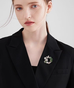 Gardenia brooch pin with white enamel petals and pearls on a black blazer lapel