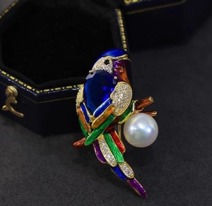 Detail of parrot brooch with colorful enamel feathers, blue gemstone and large white pearl