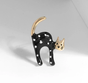 Detailed view of cat brooch with black enamel, white polka dots and gold trim finish