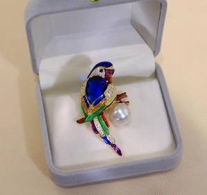 Detail of parrot brooch with colorful enamel feathers, sparkling crystals and large white pearl