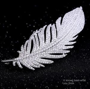 Close-up of elegant silver feather brooch with full pavé cubic zirconia on black background