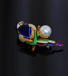 Macro detail of parrot brooch with blue teardrop gemstone and colorful enamel wing