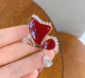 Close-up of a red enamel butterfly brooch with gold frame and sparkling crystal details