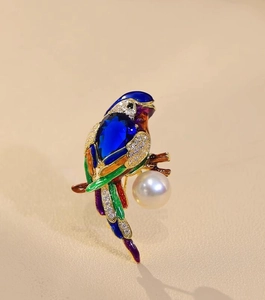 Detail of parrot brooch featuring blue gemstone body, crystal wings and a white pearl drop