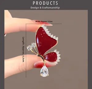 Detail view of a red crystal butterfly brooch with golden alloy and teardrop pendant