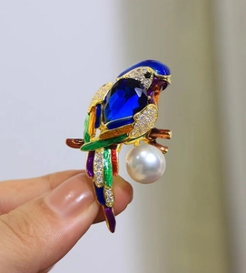 Macro detail of parrot brooch featuring vibrant enamel feathers and a large white pearl drop