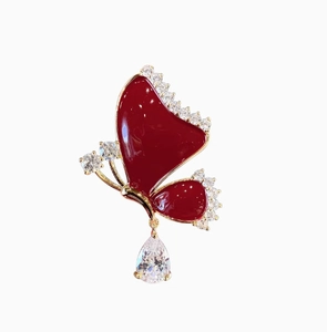 Macro detail of red enamel butterfly brooch with gold plating and pear-cut drop zircon
