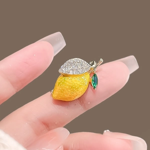 Détail de la broche citron en émail jaune avec des feuilles ornées de cristaux brillants