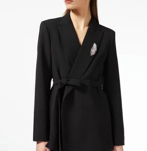 Silver feather brooch with textured metal finish pinned to a elegant black suit lapel