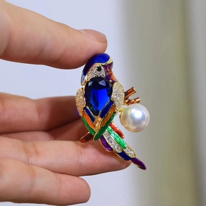 Exquisite parrot brooch featuring blue gemstone and pearl accents in colorful enamel finish