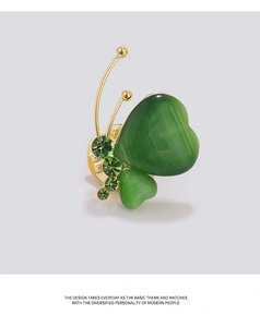 Détail de la broche papillon en pierre œil de chat verte avec des ailes dorées élégantes
