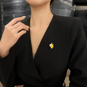 Détail d'une broche citron jaune avec cristaux fixée sur une veste de tailleur noire