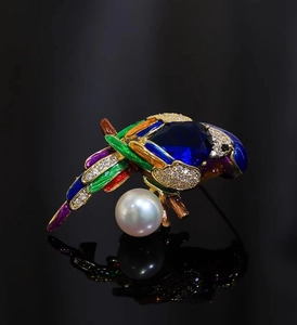 Macro shot of parrot brooch with deep blue faceted gemstone, white pearl, and enamel wings
