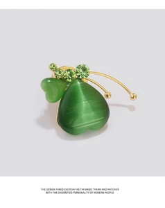 Détail macro de la broche cœur en œil de chat vert avec strass et base en métal doré