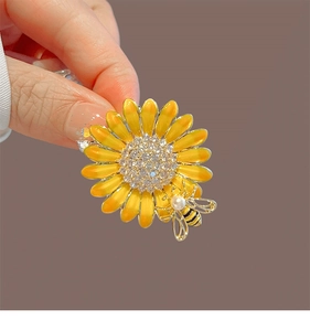 Détail d'une broche tournesol en émail avec strass brillants et motif petite abeille
