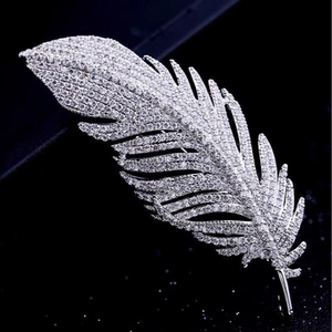 Elegant silver feather brooch with sparkling crystals on dark background for suits