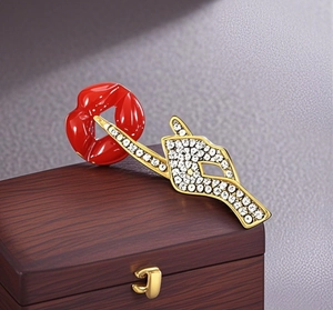 Detail view of a luxury red lip brooch with gold enamel and sparkling crystal inlay