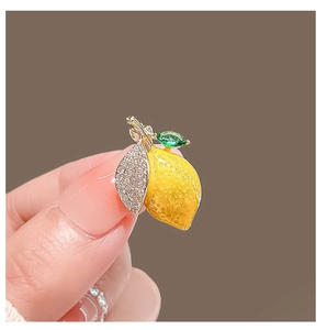 Broche citron jaune mignonne avec feuilles vertes et strass brillants sur fond marron