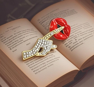 Macro shot of red enamel lips and crystal brooch on book pages for suit accessories