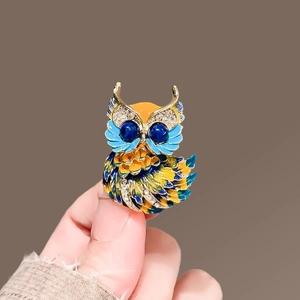 Détail de la broche chouette avec émail coloré et yeux en pierres bleues