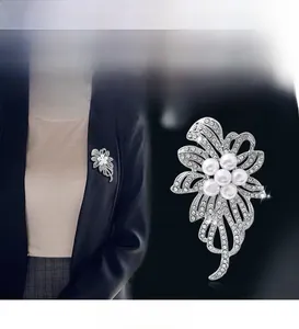 Détail d'une broche fleur argentée avec perles et strass sur une veste sombre