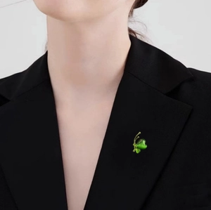 Broche papillon élégante en œil de chat vert avec ailes dorées sur un blazer noir