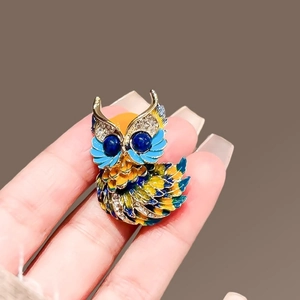 Détails d'une broche hibou en émail avec gemmes bleues et cristaux étincelants sur métal