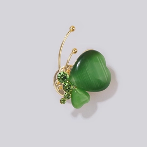 Élégante broche papillon avec ailes cœur en œil-de-chat vert et accents en cristal