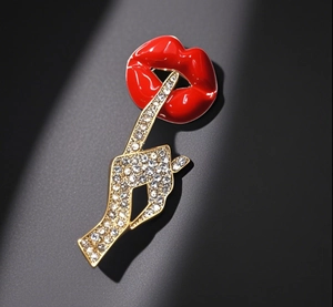 Detail of red enamel lips and crystal-encrusted hand brooch in gold-plated finish