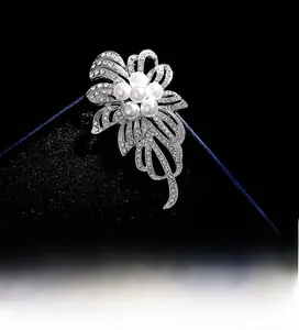Détail d'une broche fleur argentée ornée de perles blanches et de strass étincelants