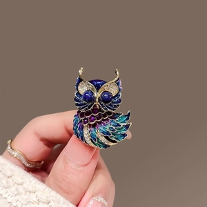 Vue détaillée d'une broche hibou avec émail bleu et strass brillants sur fond neutre