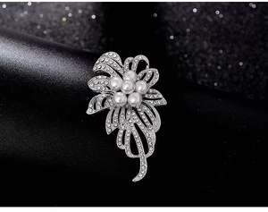 Vue macro détaillée d'une broche fleur argentée avec cinq perles blanches et des strass brillants