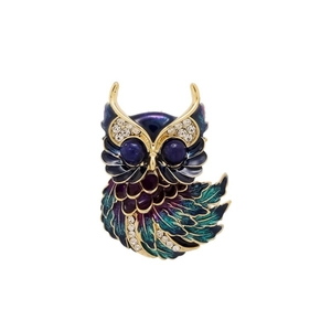 Détail macro de la broche hibou avec dégradé d'émail coloré, bordure dorée et cristaux brillants