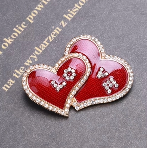 Detail of red enamel heart brooch with rhinestones and LOVE lettering on dark texture
