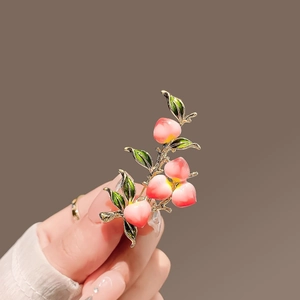 Detailed view of peach fruit brooch with pink gradient fruits and green enamel leaves