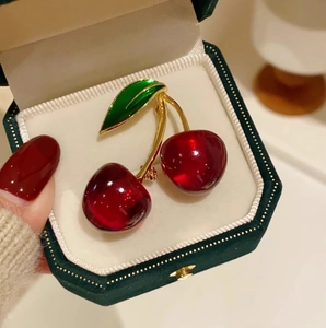 Elegant cherry brooch with red resin fruit and green leaf in a green velvet jewelry box